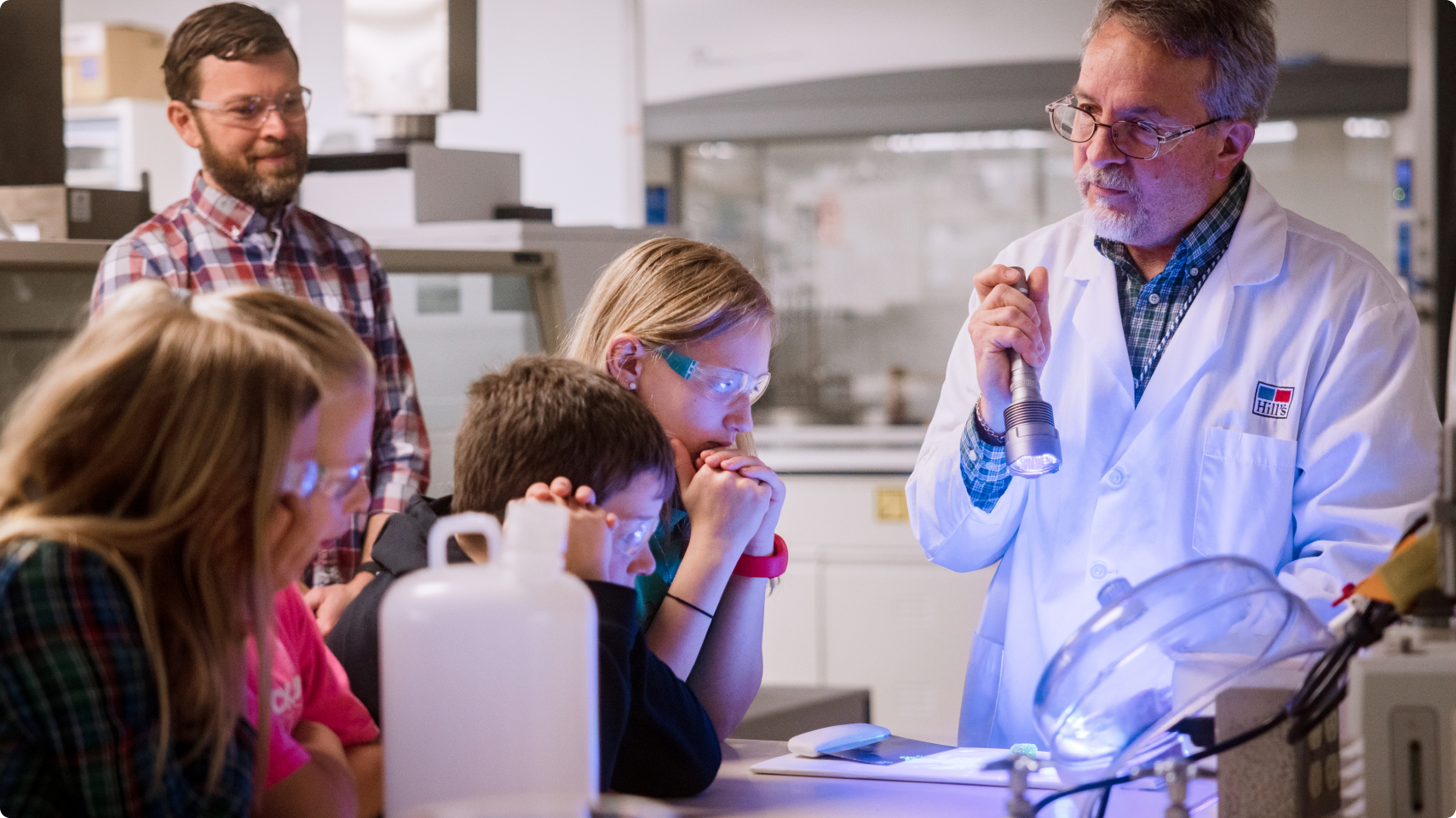 A Hill's scientist holds a torch light to demonstrate lab work to children